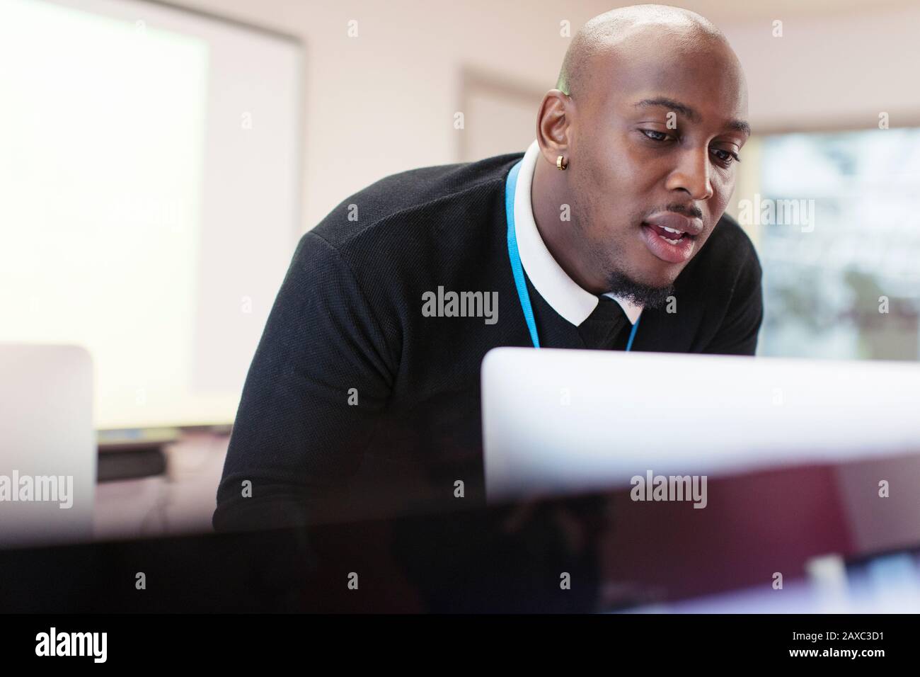 Instructeur masculin concentré sur l'ordinateur en classe Banque D'Images