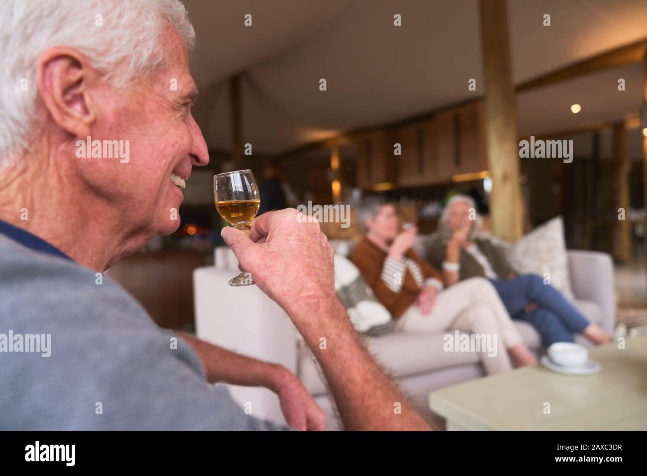 Un homme expérimenté et heureux buvant du cordial avec des amis dans l'hôtel Banque D'Images