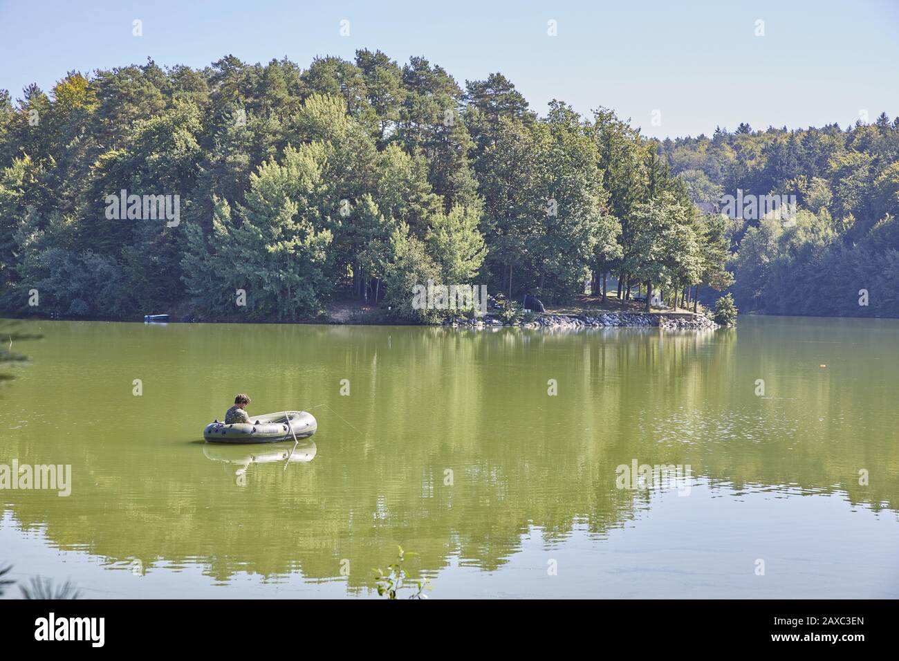Homme à cheval sur un radeau pneumatique dans le lac de Smartinsko, région de Savinjska, Slovénie Banque D'Images