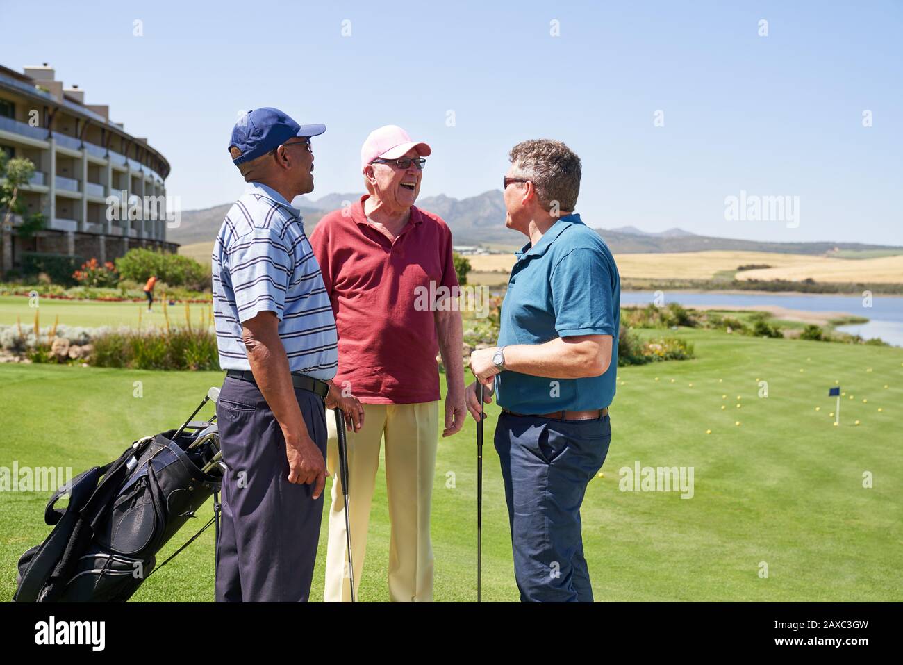 Heureux hommes golf amis parler sur le terrain de golf ensoleillé Banque D'Images