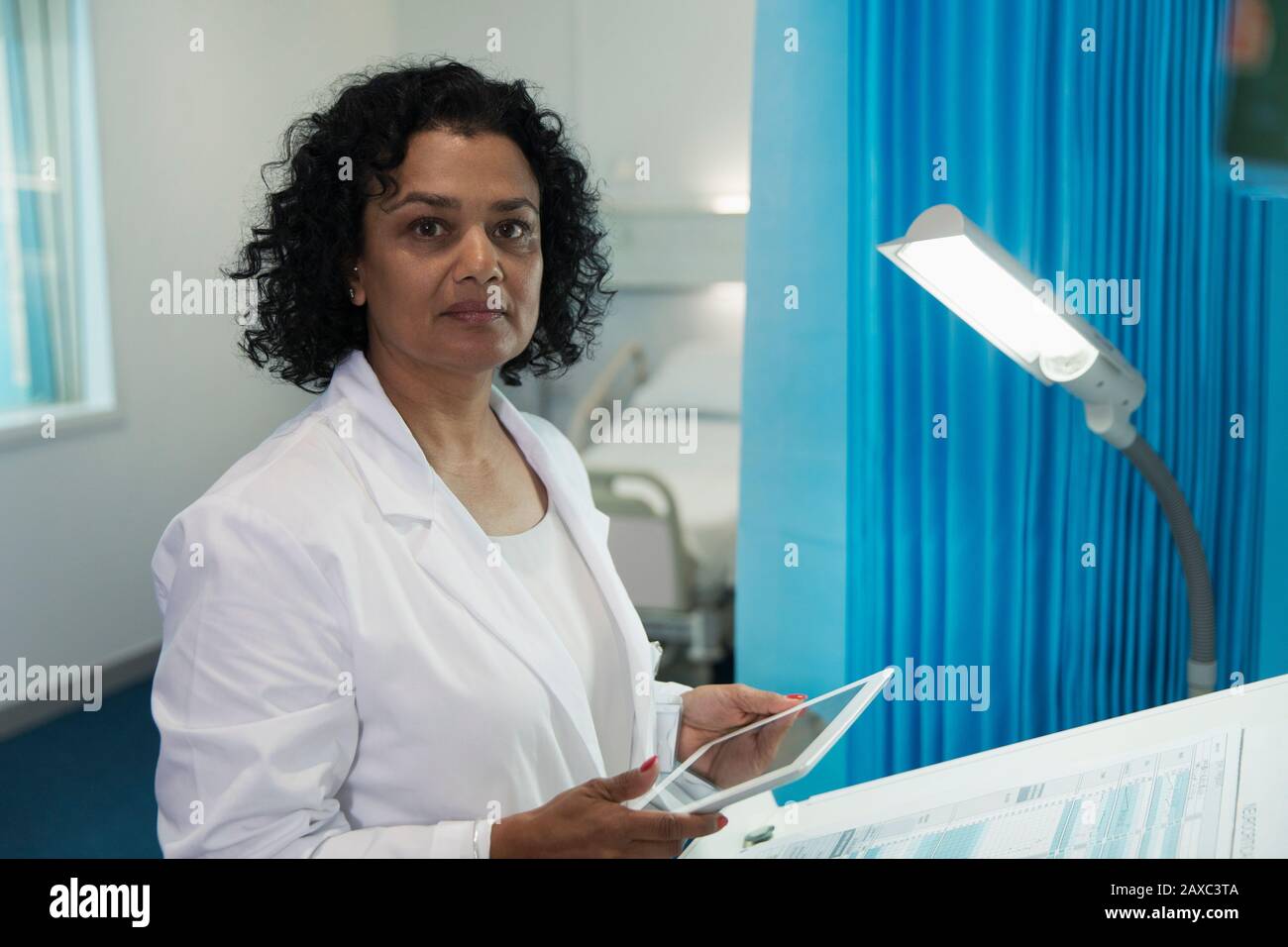 Portrait confiant, déterminé médecin de femme utilisant la tablette numérique dans la salle d'hôpital Banque D'Images