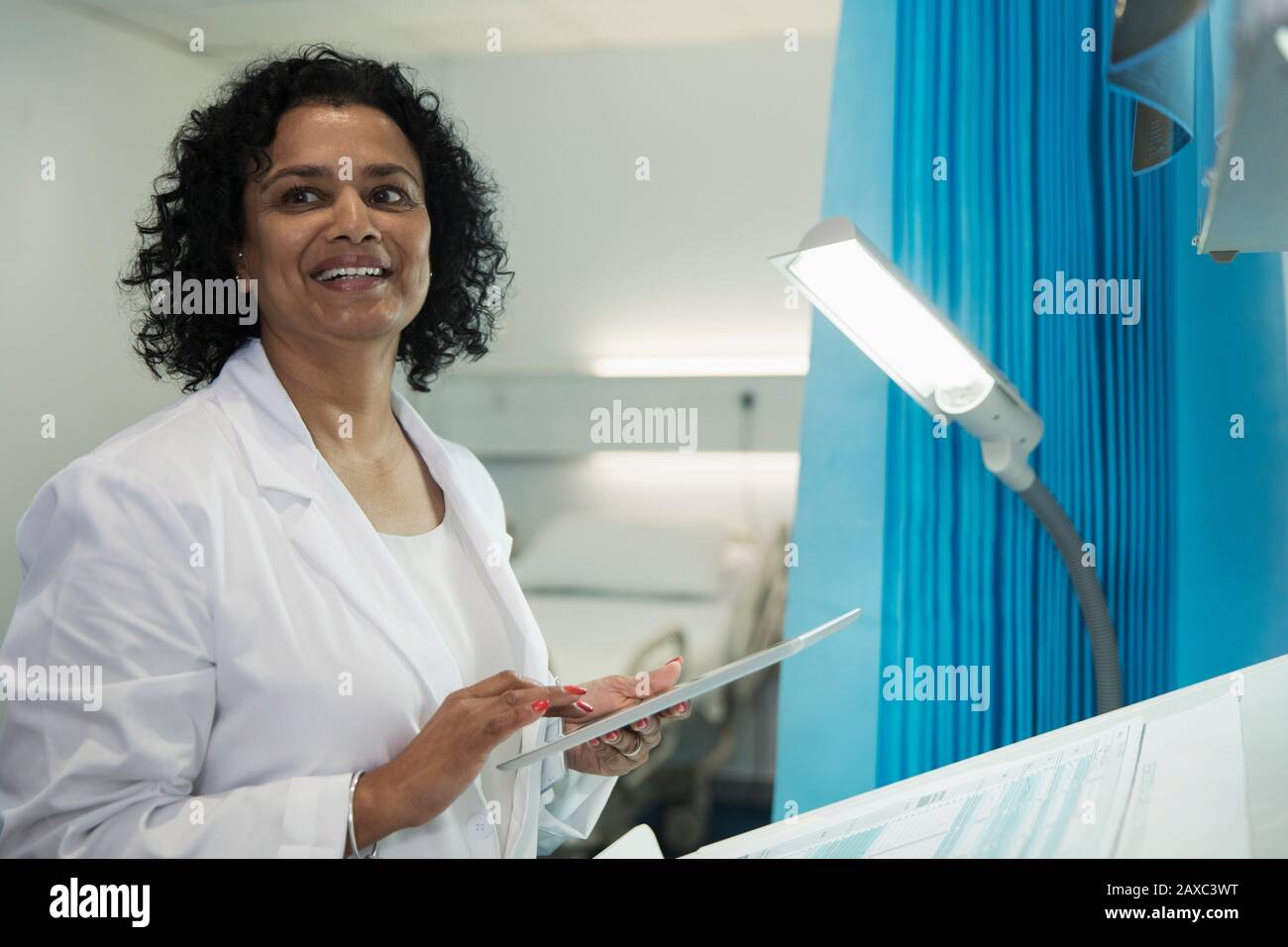 Médecin souriant utilisant une tablette numérique dans la salle d'hôpital Banque D'Images