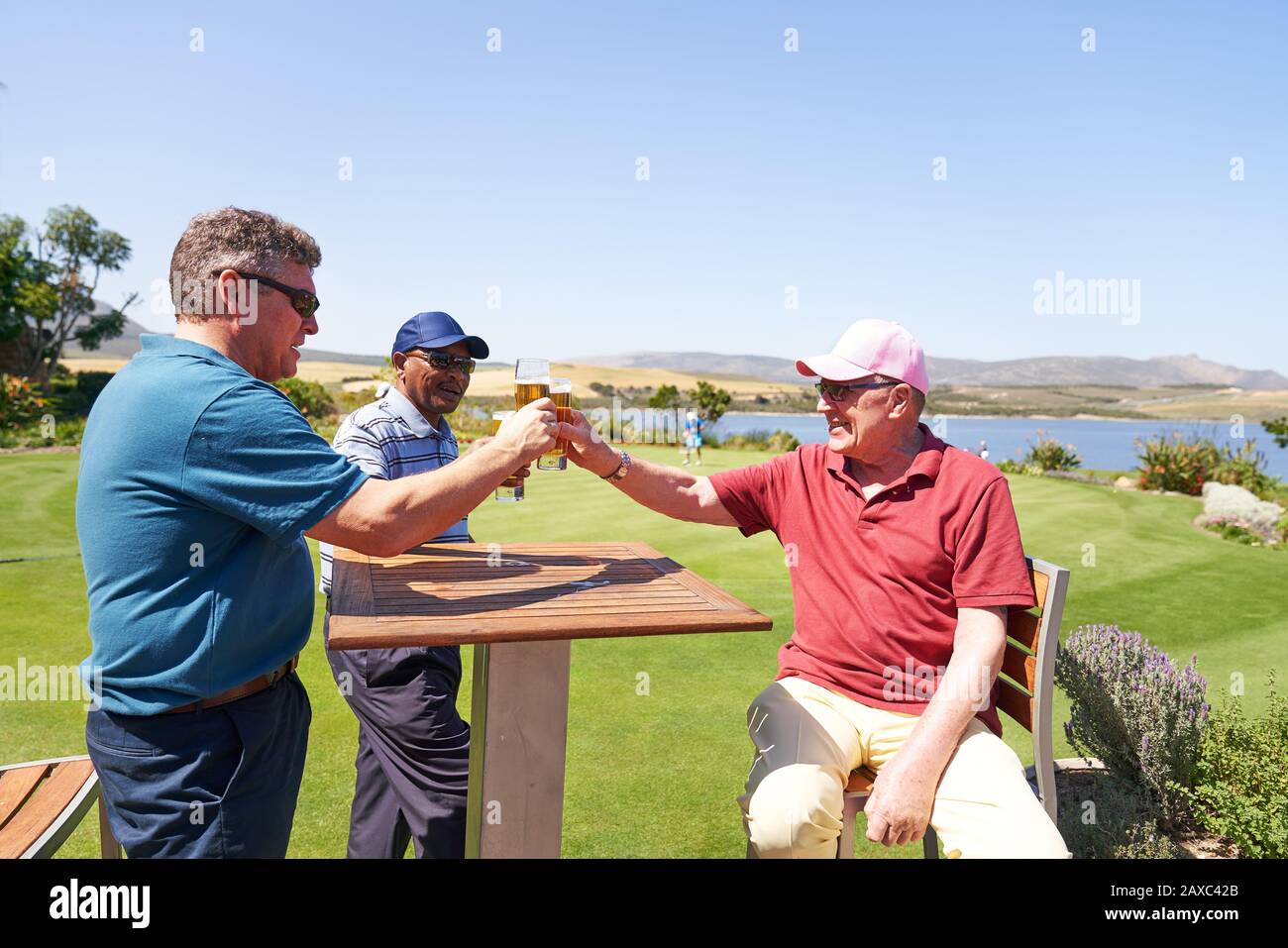Les golfeurs de sexe masculin adultes boivent de la bière sur le patio ensoleillé du pavillon de golf Banque D'Images