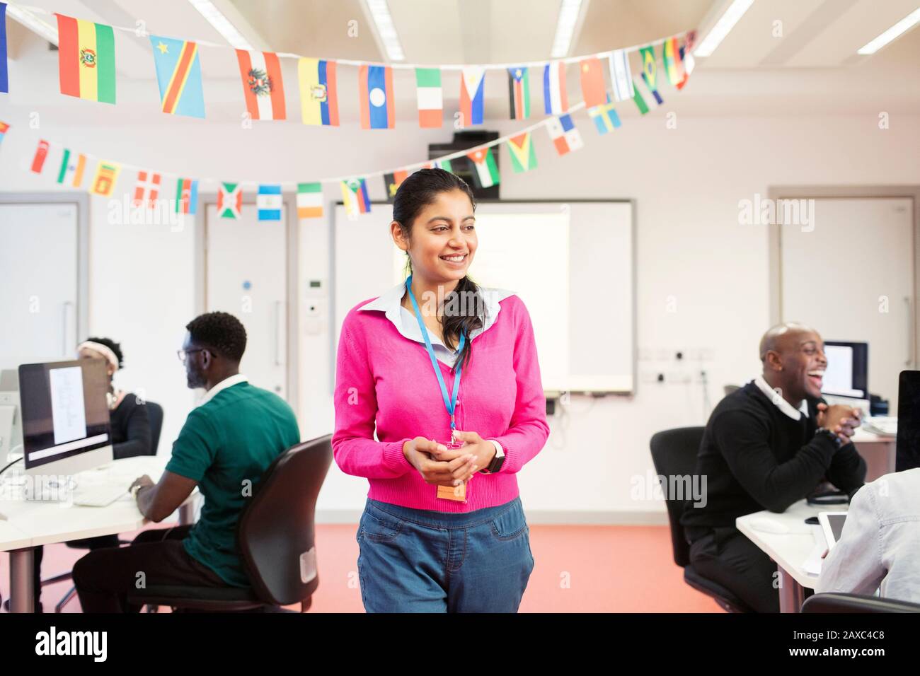 Un instructeur d'université de communauté féminine souriant et confiant dans une salle de classe de laboratoire informatique Banque D'Images