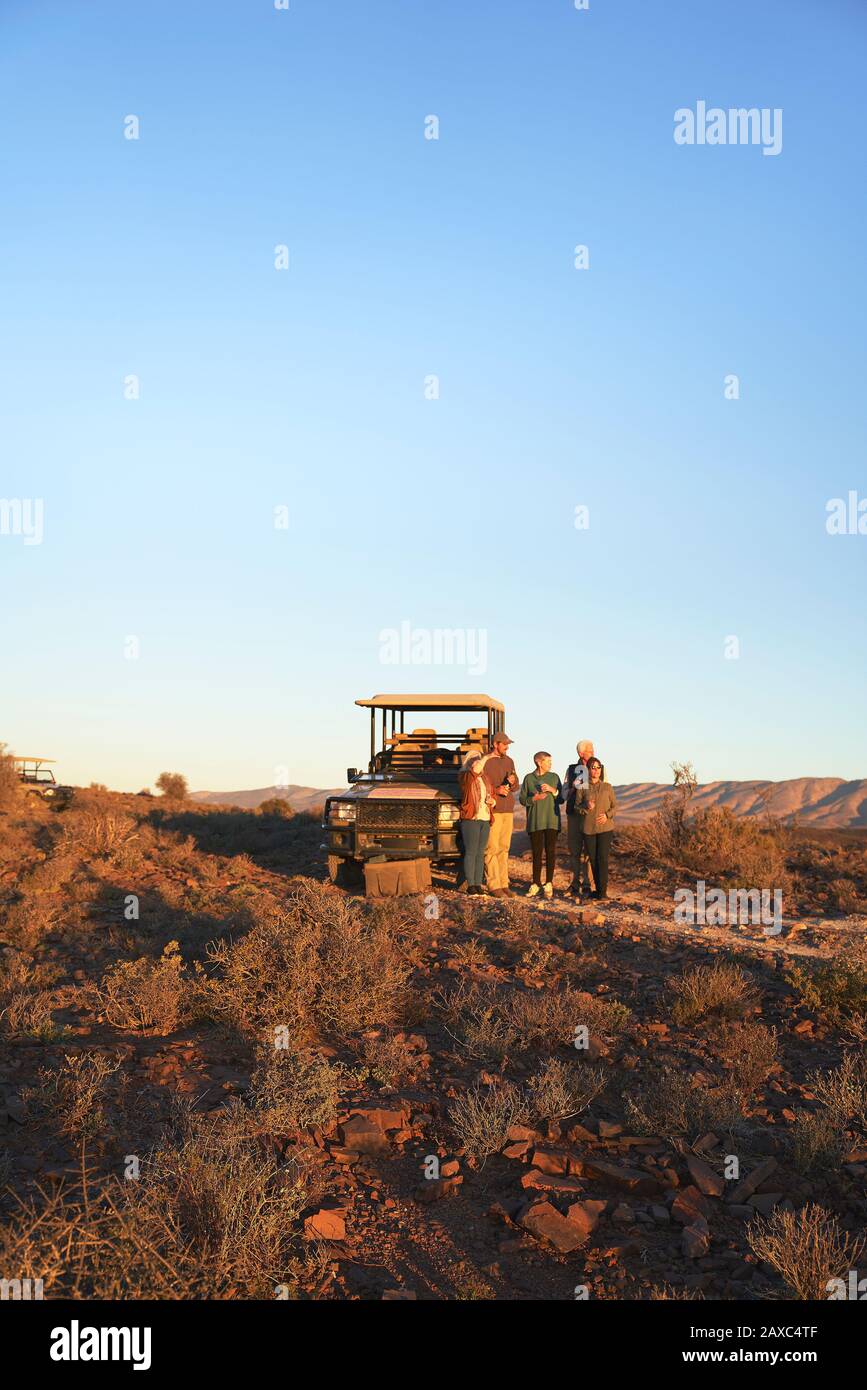 Safari groupe de visites debout à l'extérieur du véhicule tout-terrain dans une prairie ensoleillée Banque D'Images