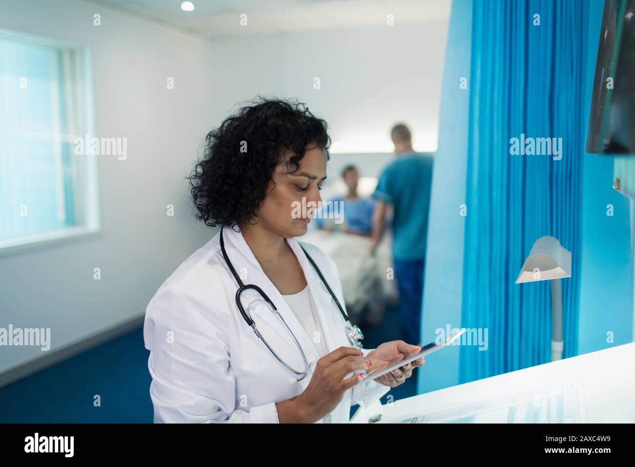 Médecin féminin concentré utilisant une tablette numérique dans la salle d'hôpital Banque D'Images