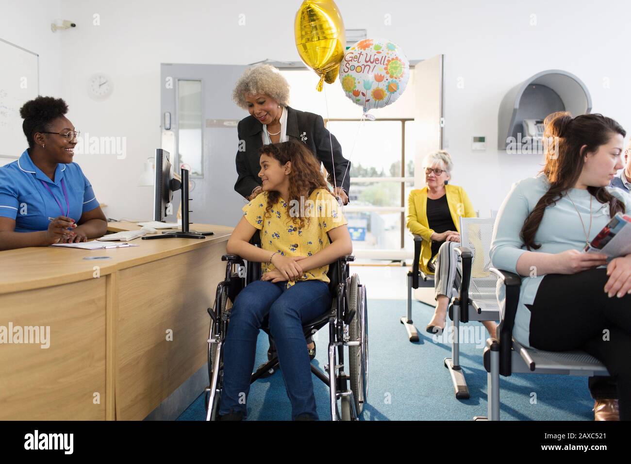 La réceptionniste accueille une fille patient en fauteuil roulant dans la clinique Banque D'Images