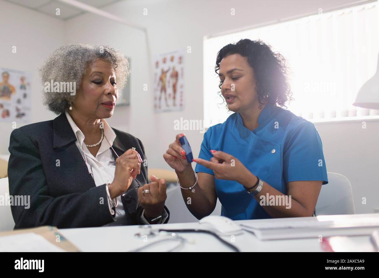 Médecin femme enseignant aux patients diabétiques comment utiliser le glucometer dans le cabinet de médecins Banque D'Images