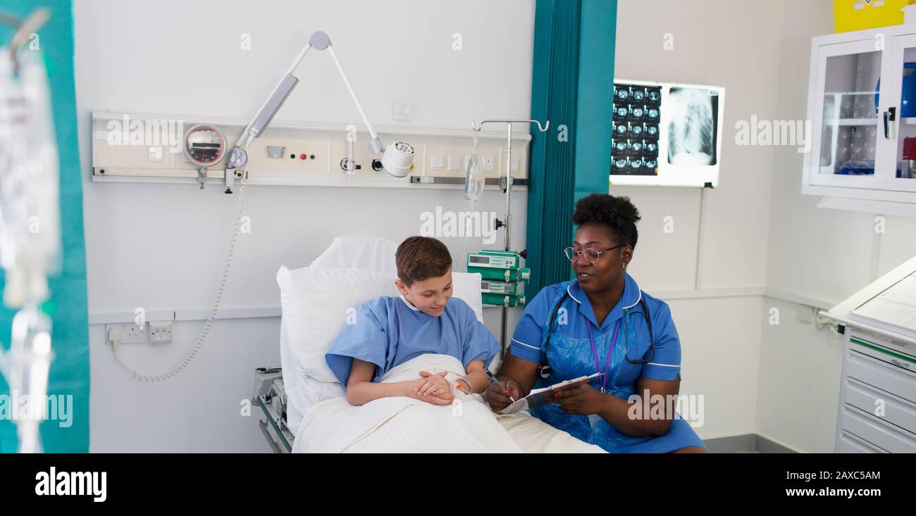 Infirmière féminine parlant avec un jeune patient dans la chambre de l'hôpital Banque D'Images