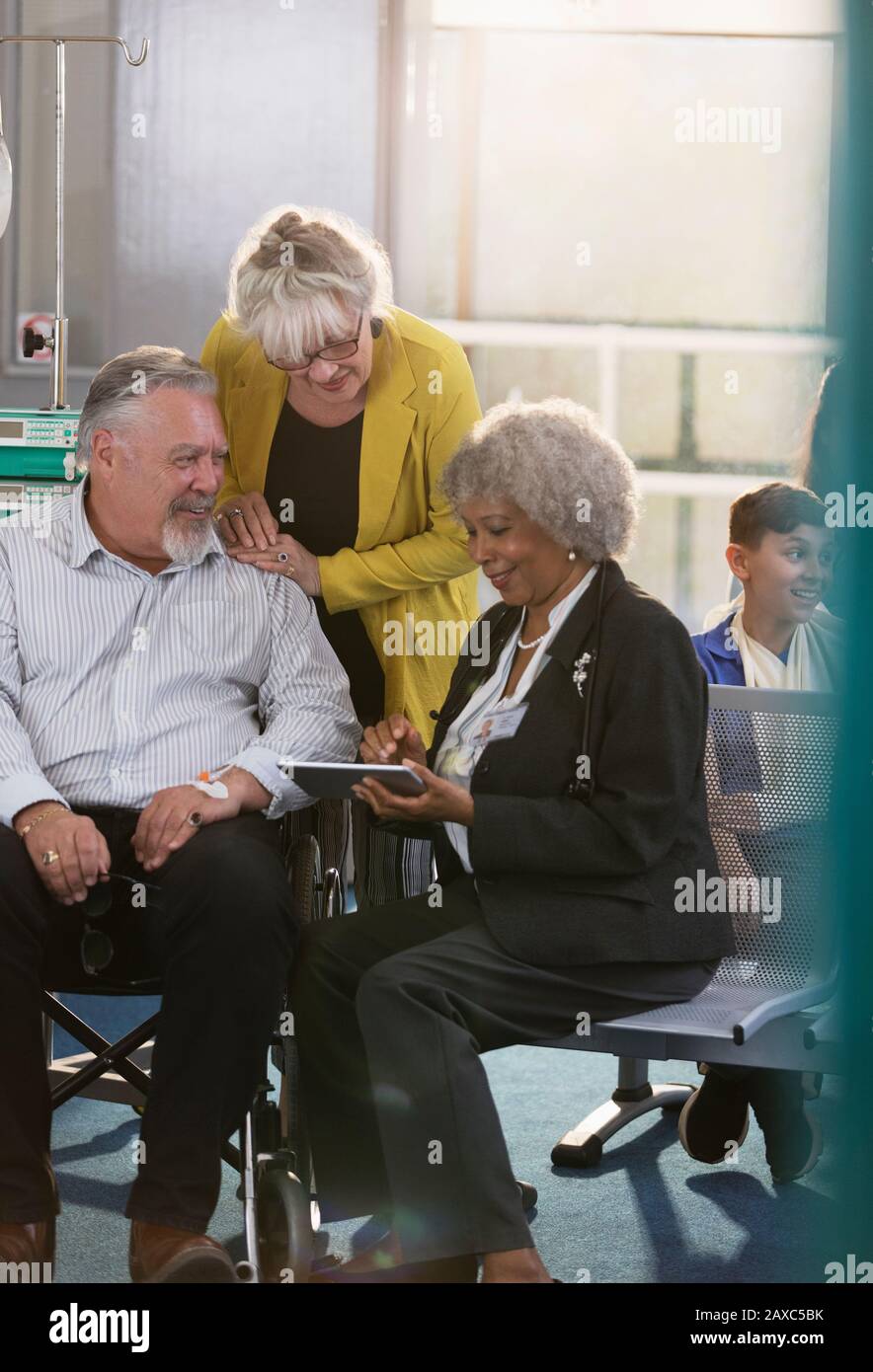 Médecin avec tablette numérique parlant à couple dans le hall de la clinique Banque D'Images