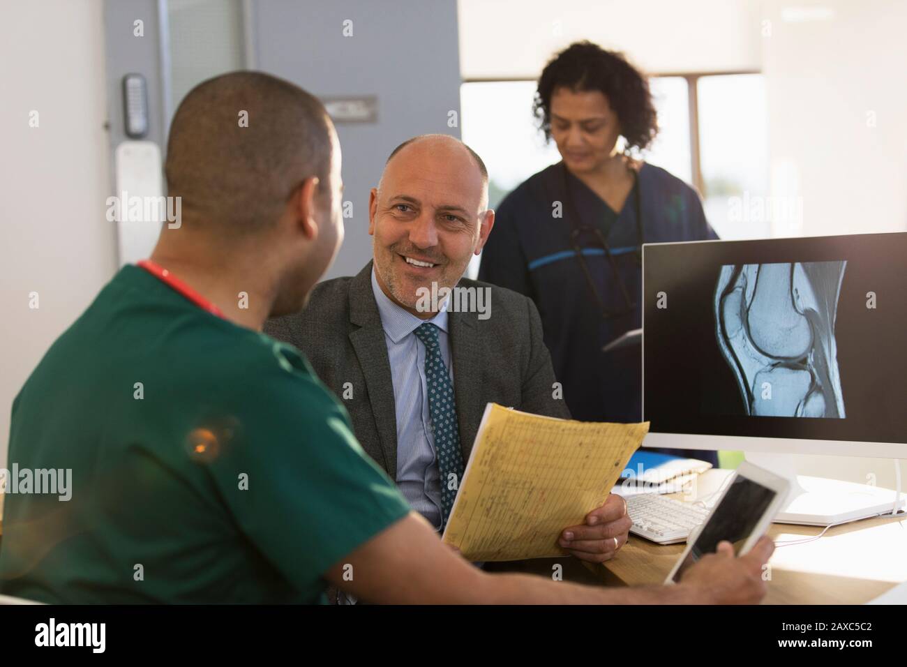 Médecin et infirmière discutant de la radiographie numérique à l'ordinateur en clinique Banque D'Images