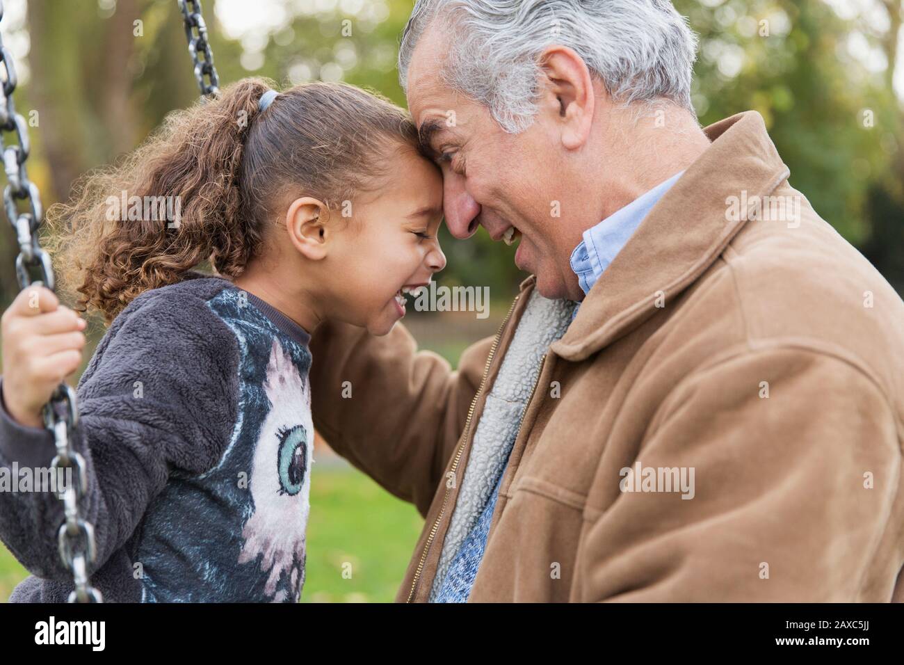 Un grand-père et une petite-fille espiègles lors d'un swing sur le terrain de jeu Banque D'Images