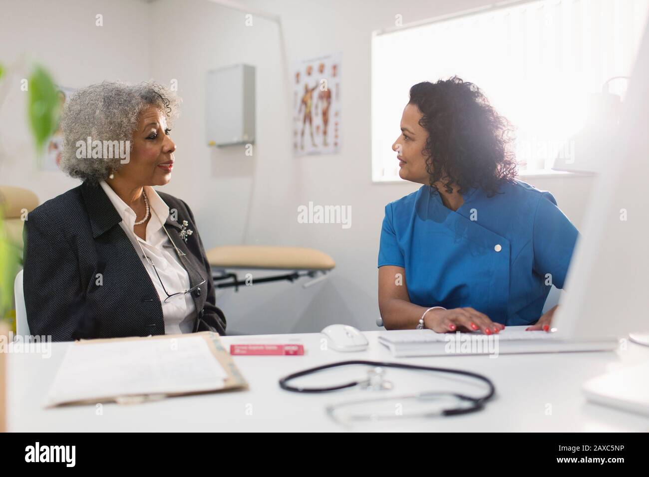 Médecin de sexe féminin en parlant avec un patient senior dans un bureau de médecins Banque D'Images
