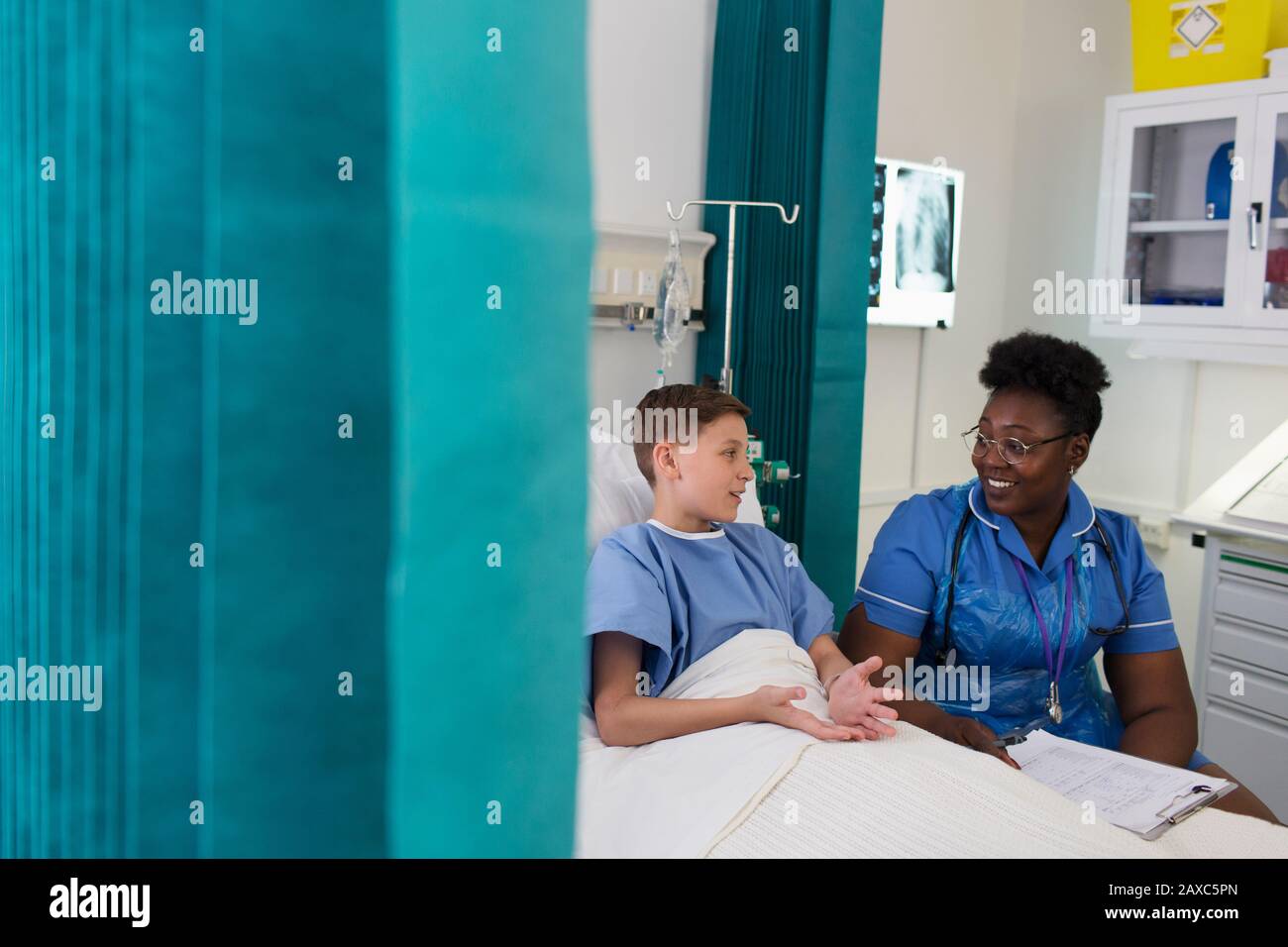 Infirmière féminine parlant à un jeune patient dans la chambre de l'hôpital Banque D'Images