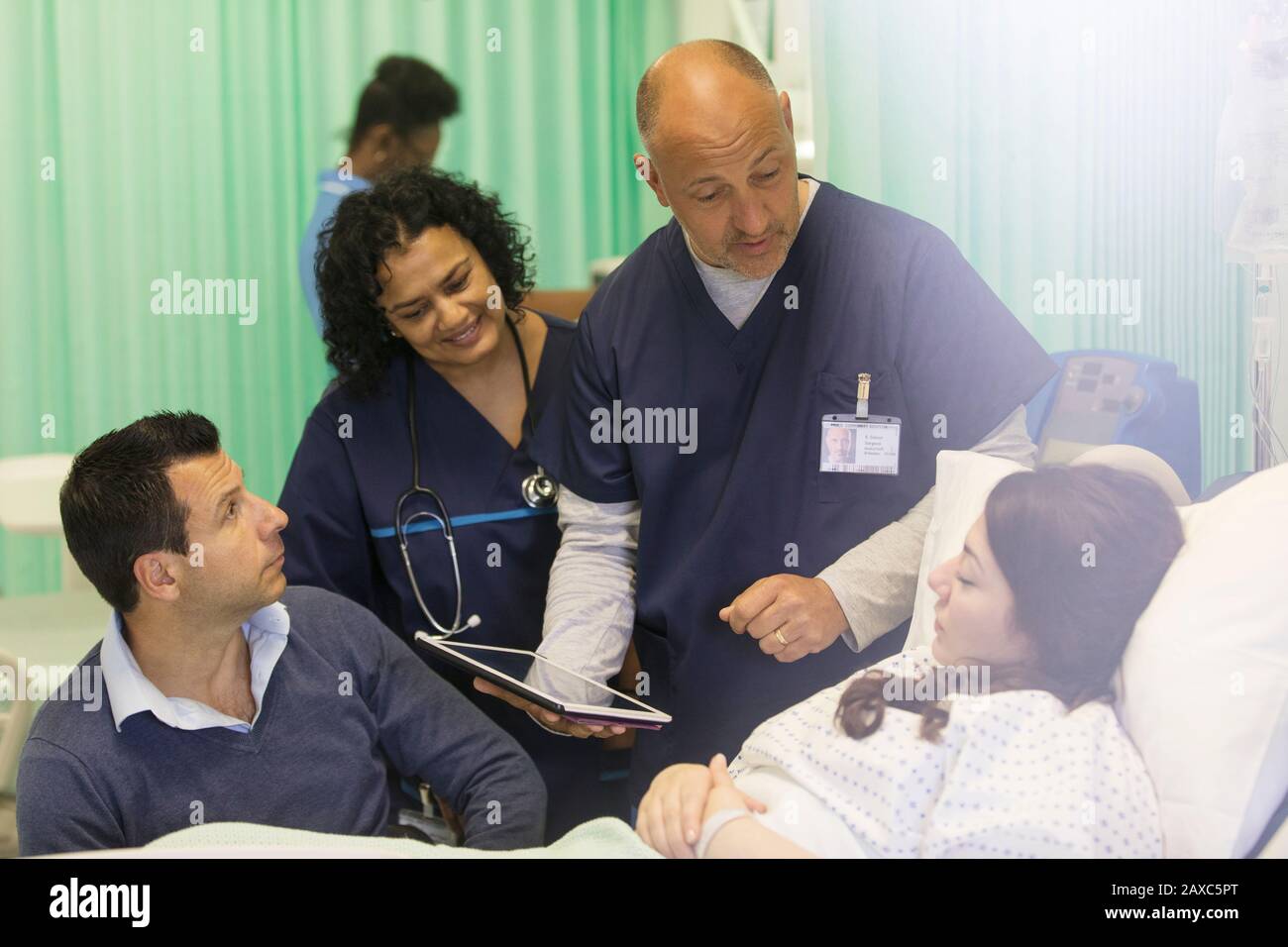Médecins avec tablette numérique en train de faire des rondes, en parlant avec le patient dans le service hospitalier Banque D'Images