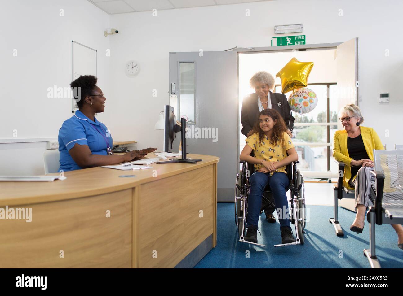 Femme poussant une fille patient en fauteuil roulant à la réception de la clinique Banque D'Images