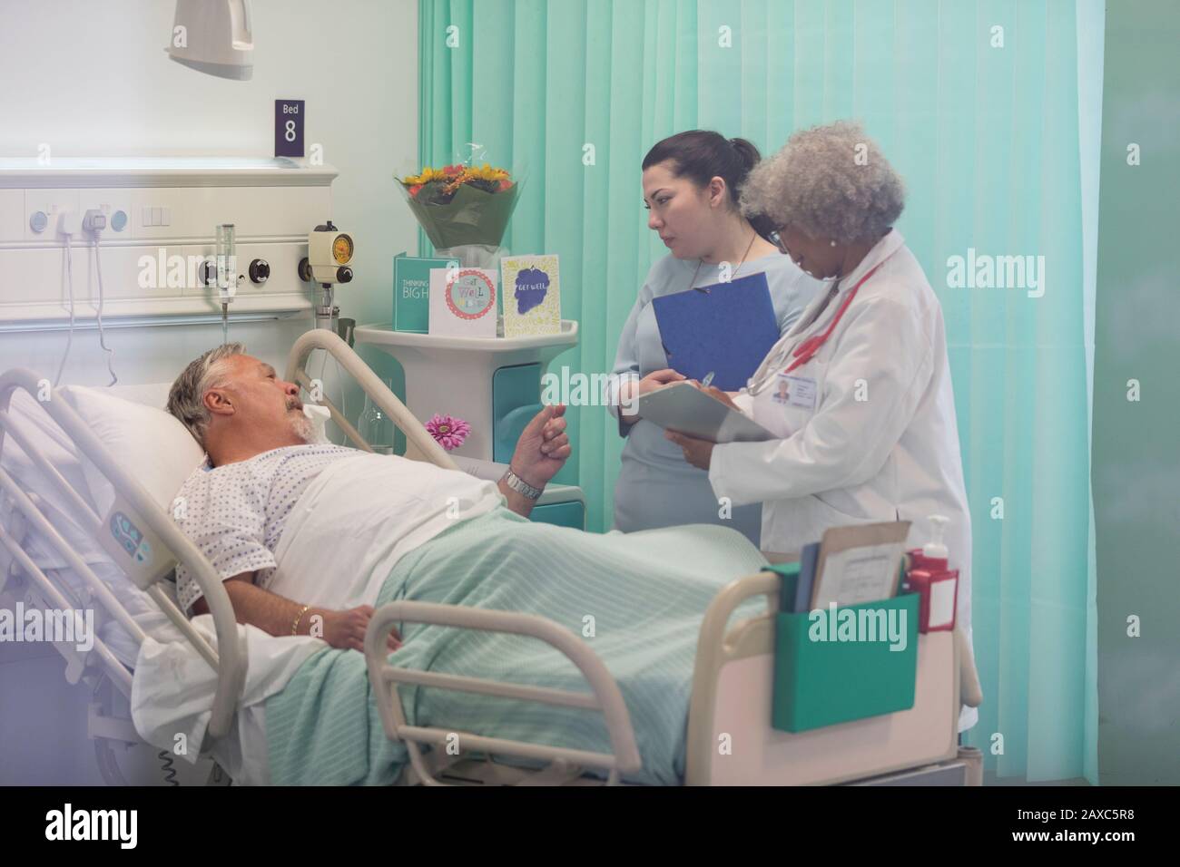 Médecins avec dossier médical effectuant des rondes, en parlant avec le patient senior dans la salle d'hôpital Banque D'Images