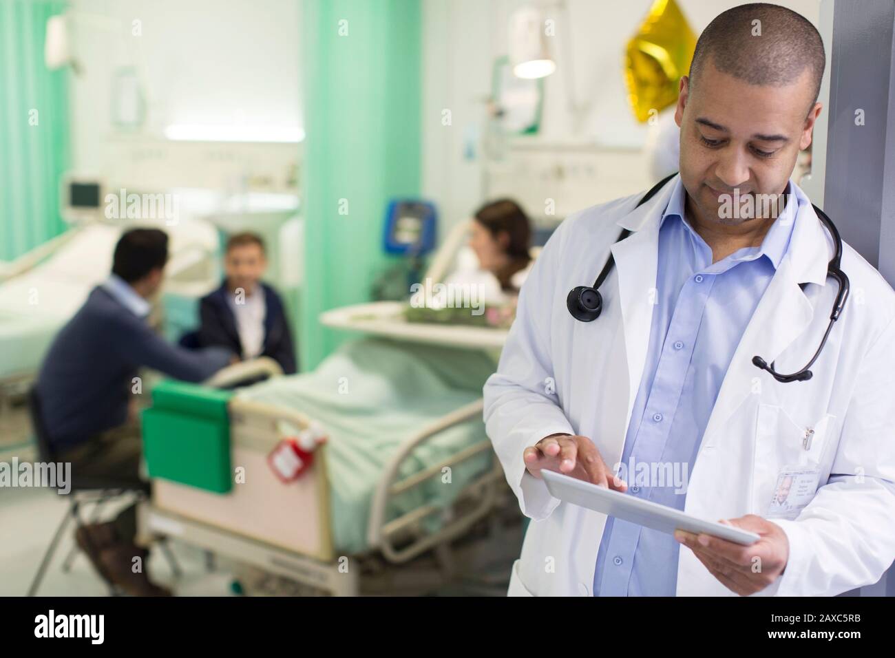 Médecin masculin avec tablette numérique en train de faire des rondes dans le service hospitalier Banque D'Images