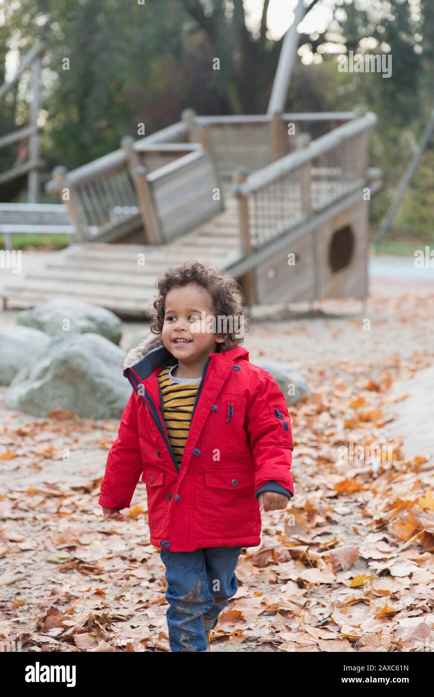 Jeune garçon souriant marchant dans le parc d'automne Banque D'Images