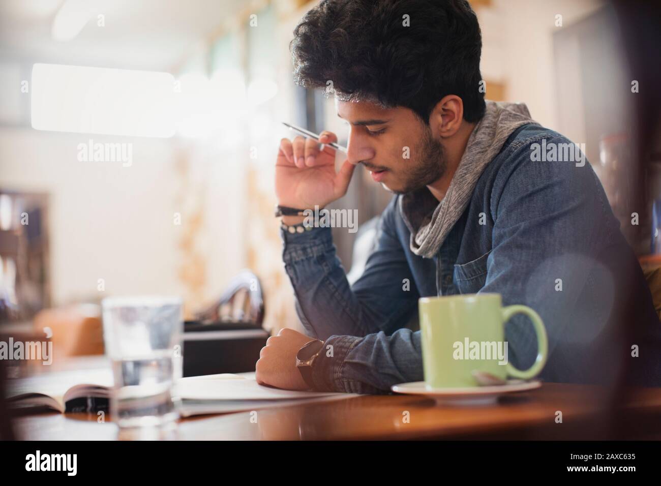 Jeune étudiant de l'université de sexe masculin concentré étudiant dans un café Banque D'Images