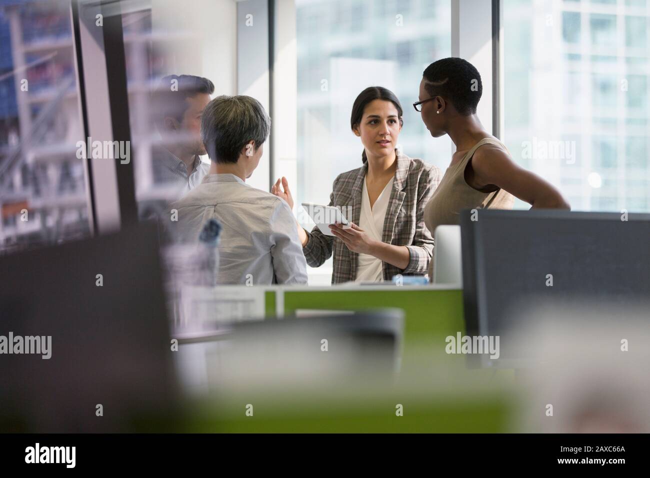 Les professionnels qui parlent une tablette numérique, se réunissent au bureau Banque D'Images