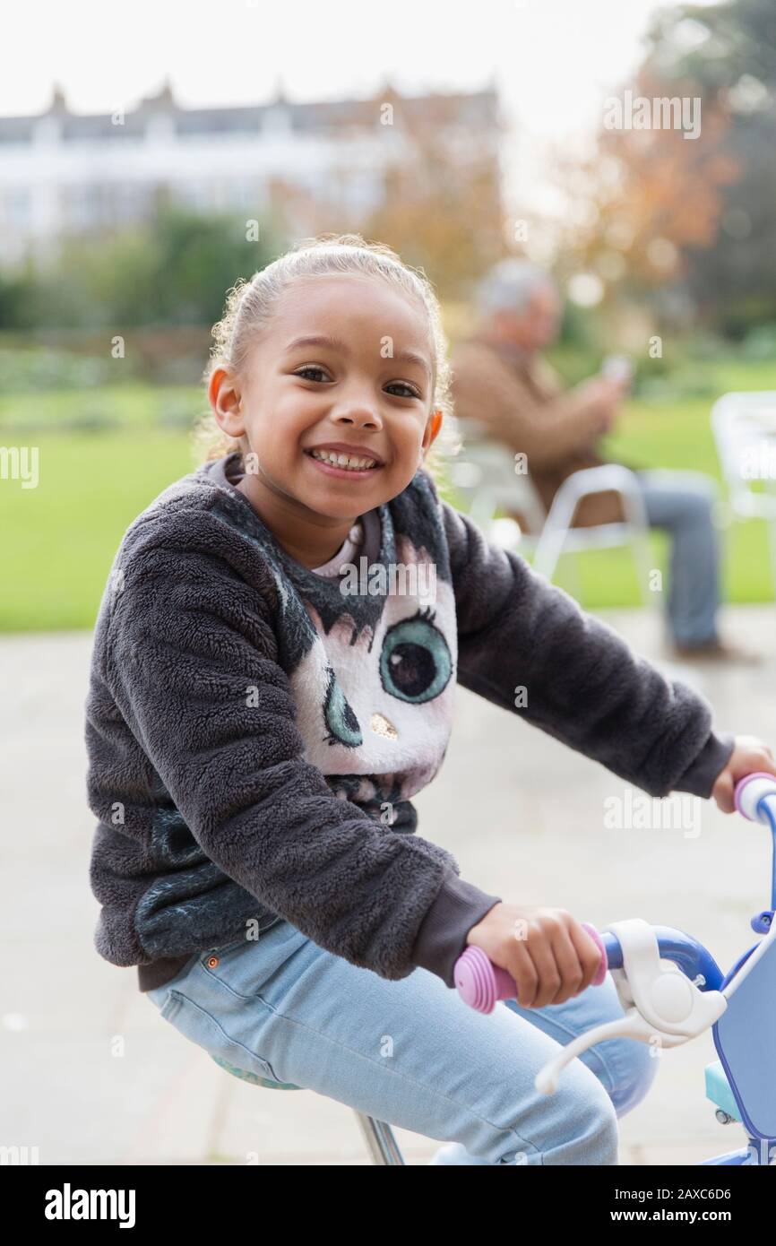 Portrait souriant fille vélo d'équitation à l'aire de jeux Banque D'Images