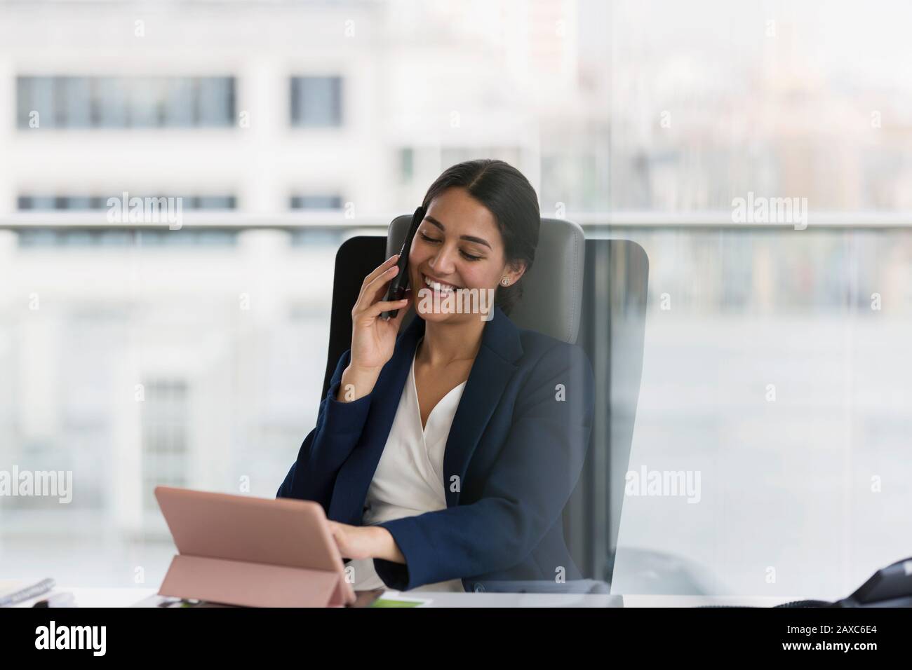 Femme d'affaires souriante parlant sur un smartphone au bureau Banque D'Images