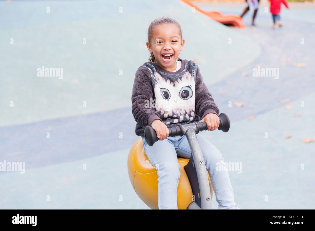 Portrait souriant, fille enthousiaste jouant à l'aire de jeux Banque D'Images