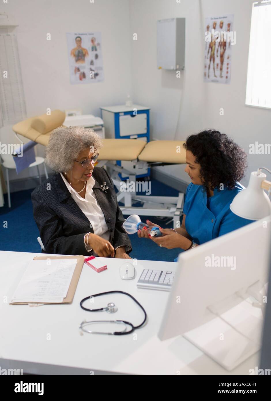 Médecin femme enseignant aux patients âgés comment utiliser l'inhalateur dans le cabinet de médecins Banque D'Images