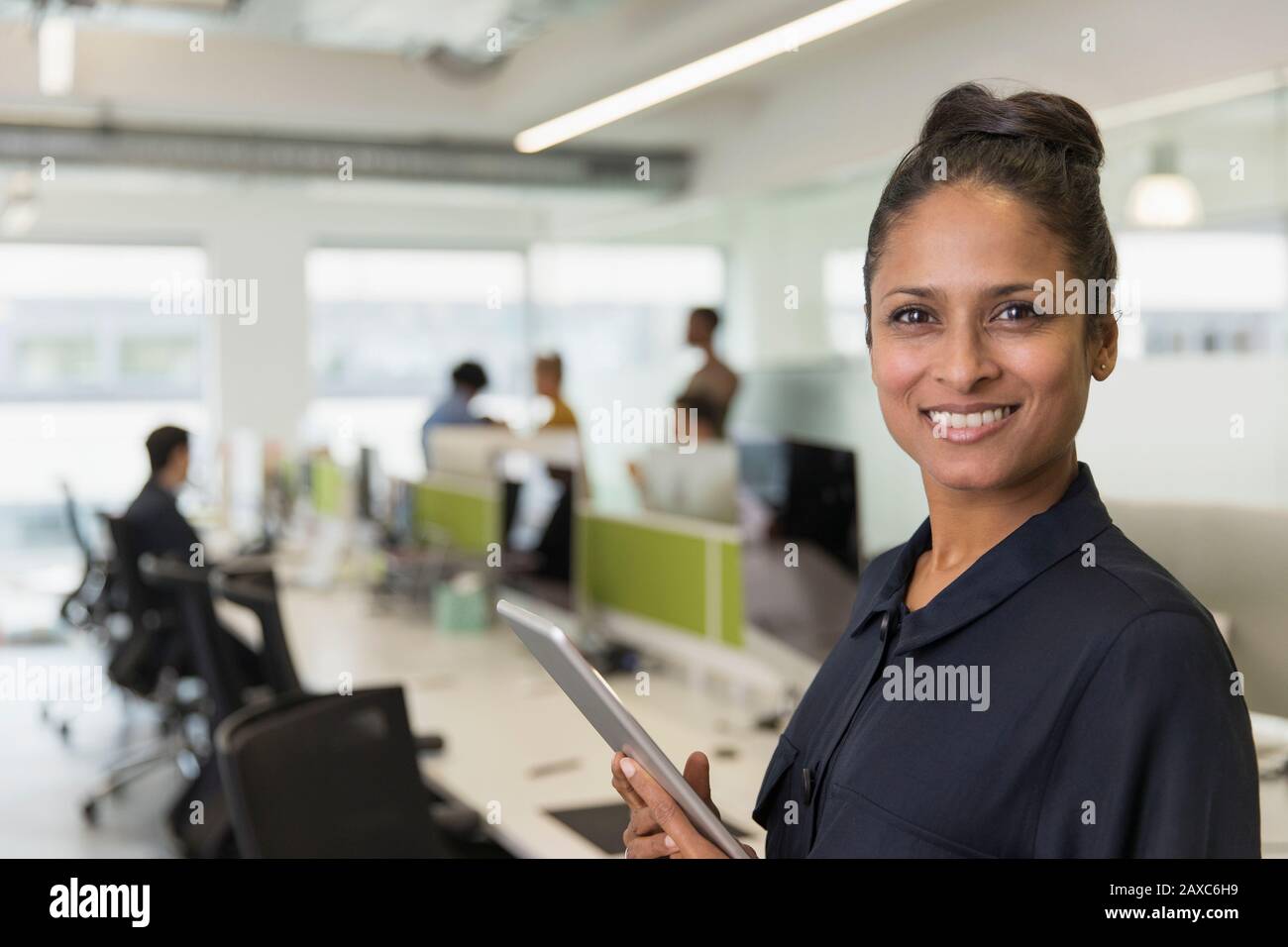 Portrait confiant femme d'affaires souriante avec tablette numérique au bureau Banque D'Images