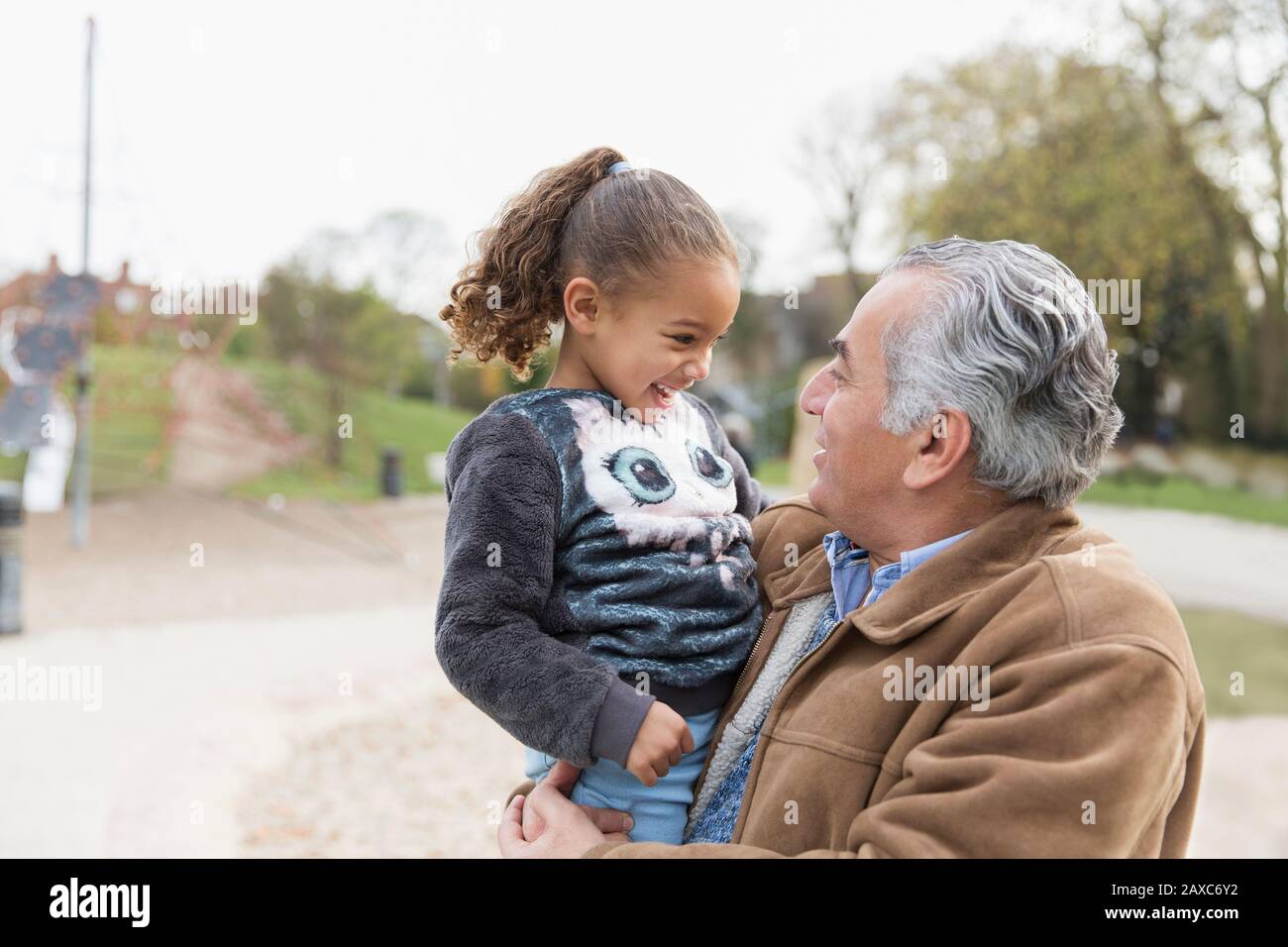 Grand-père souriant tenant la petite-fille au parc Banque D'Images