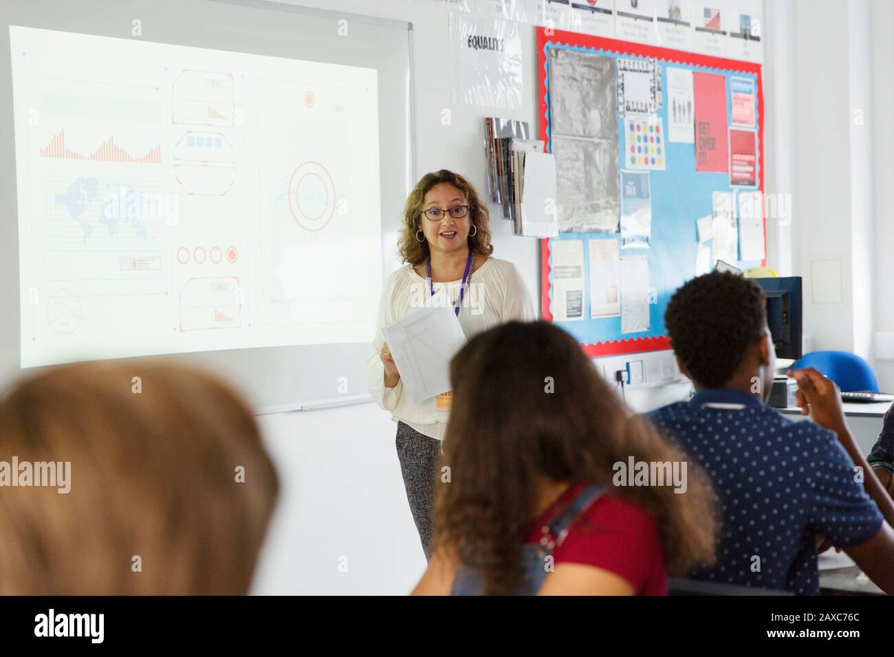 Professeur de lycée féminin menant la leçon à l'écran de projection dans la salle de classe Banque D'Images