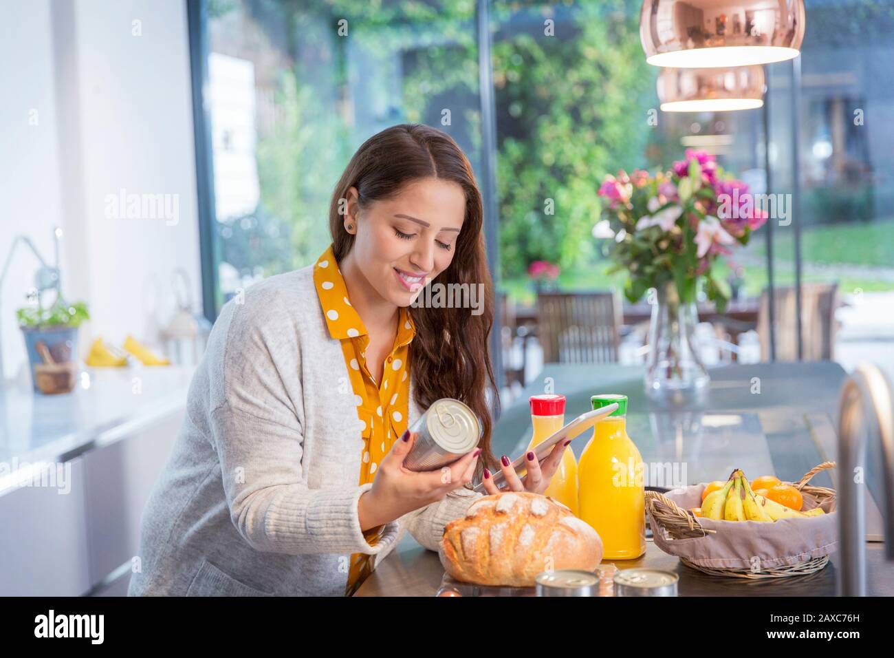 Femme souriante avec tablette numérique dans la cuisine Banque D'Images