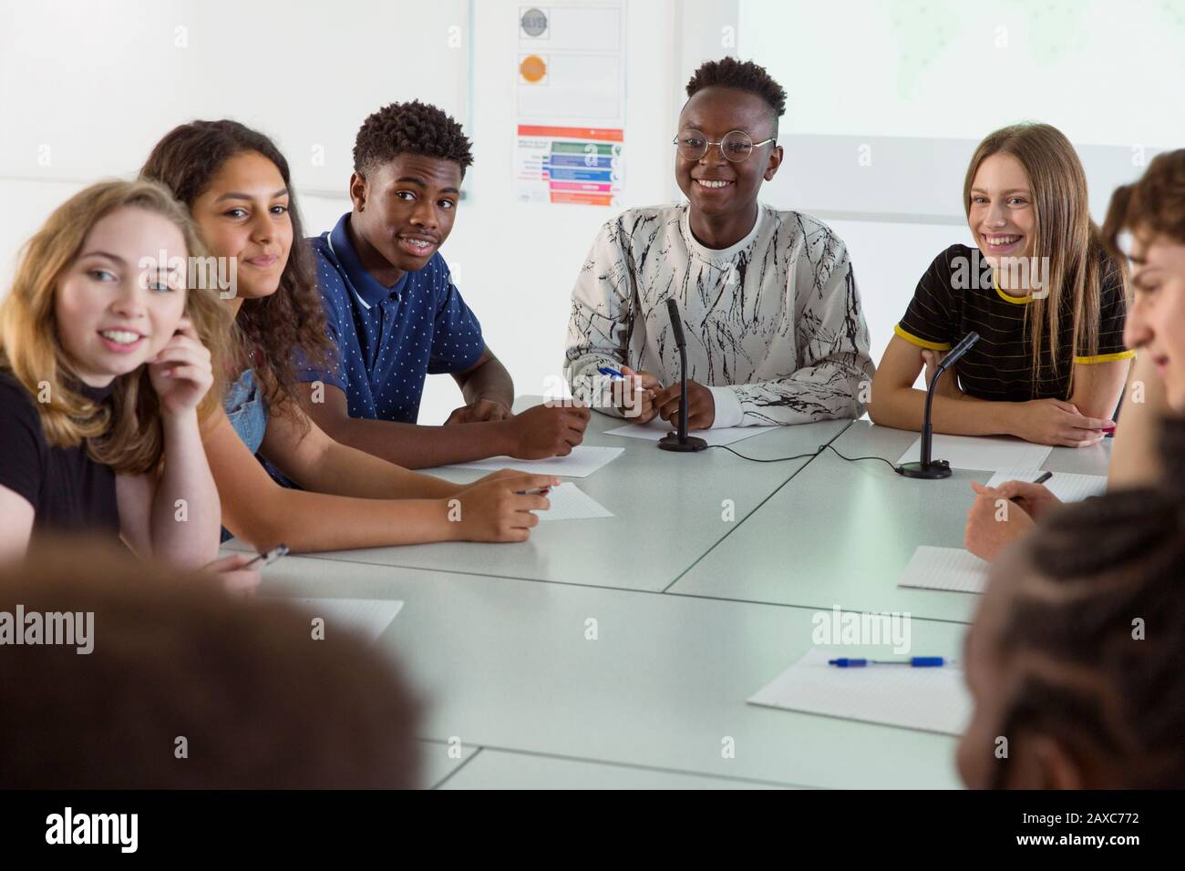 Les élèves souriants de l'école secondaire écoutent en classe de débat Banque D'Images