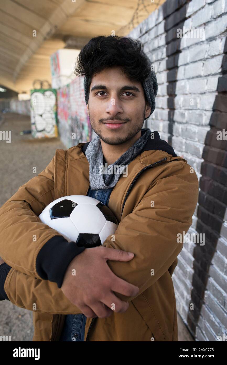 Portrait confiant jeune homme avec ballon de football dans le tunnel urbain Banque D'Images