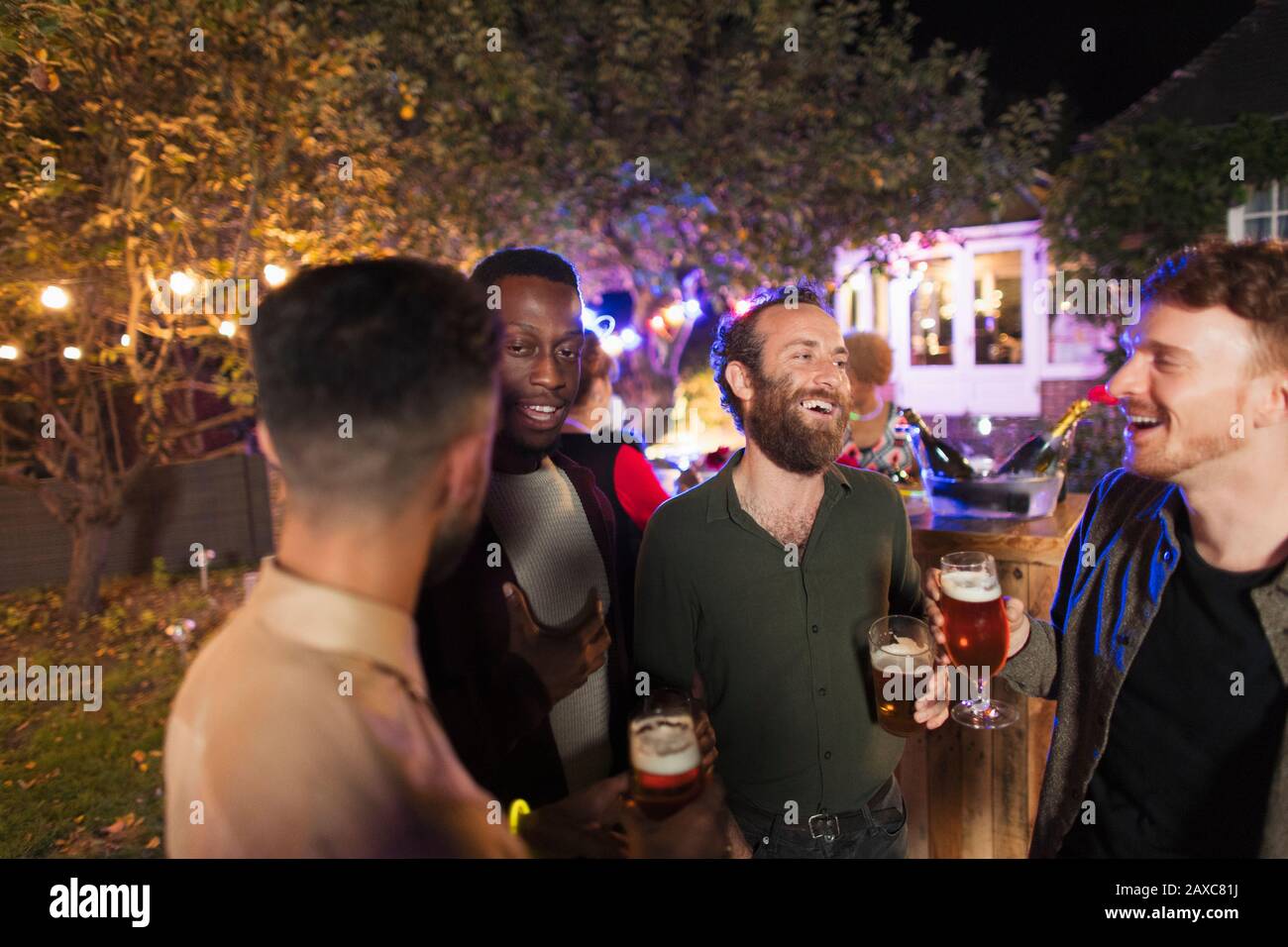 Des amis masculins parlent et boivent à la fête du jardin Banque D'Images