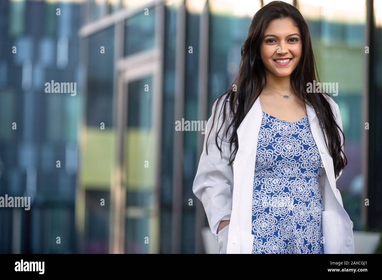 Portrait de style de vie candié d'un professionnel de la santé féminin dans un manteau blanc marchant à l'extérieur du lieu de travail Banque D'Images