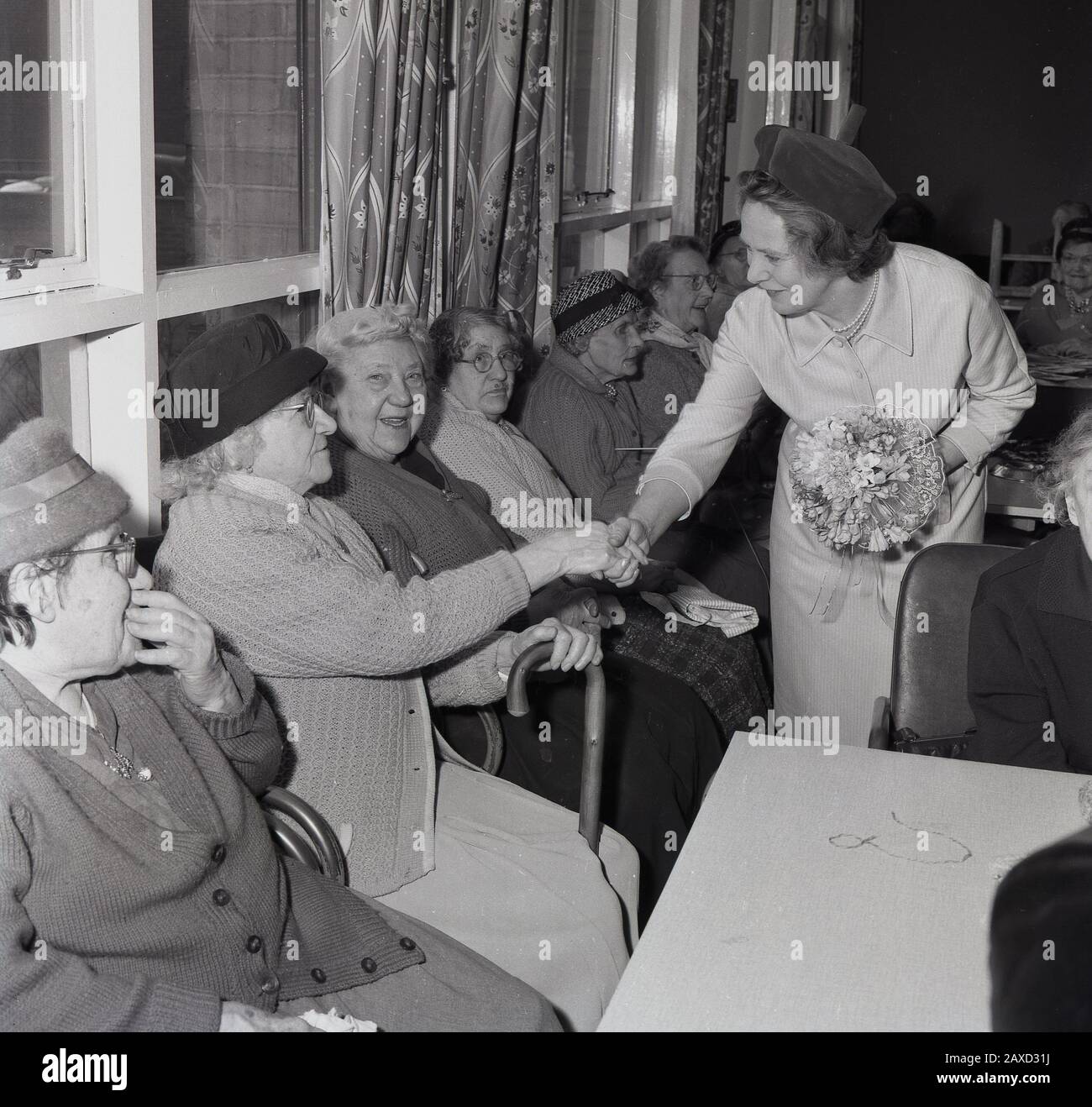 Années 1960, historique, Mme Wison, l'épouse du Premier ministre britannique, Harold Wilson, saluant les résidentes d'une maison de vieux peuples lors d'une visite dans le sud de Londres, Angleterre, Royaume-Uni. Une femme sans prétention et sans prétention qui, dit-on, aimait la poésie, les fleurs et les plaisirs simples de la maison et de la vie de famille, a soutenu son mari pendant cinq élections générales et a vécu une longue vie de 102 ans. Banque D'Images