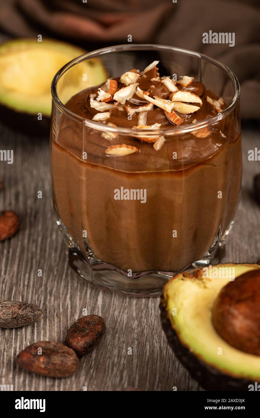 Dessert avocat avec cacao dans un verre sur une surface en bois. Produits végétaliens bruts. Banque D'Images