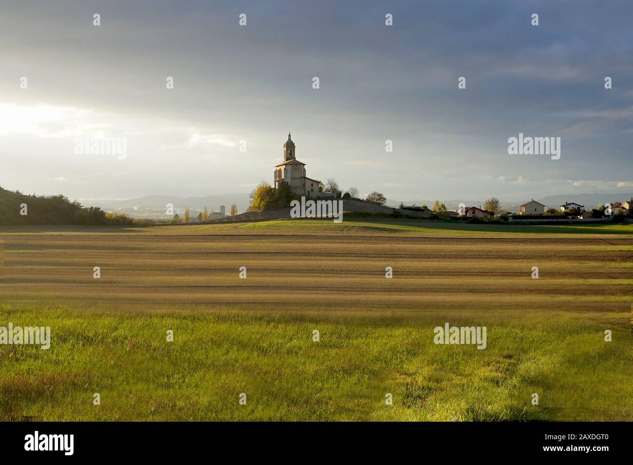 Un ciel sombre au-dessus d'une vieille église se tenait seul sur une colline baignée de soleil Banque D'Images