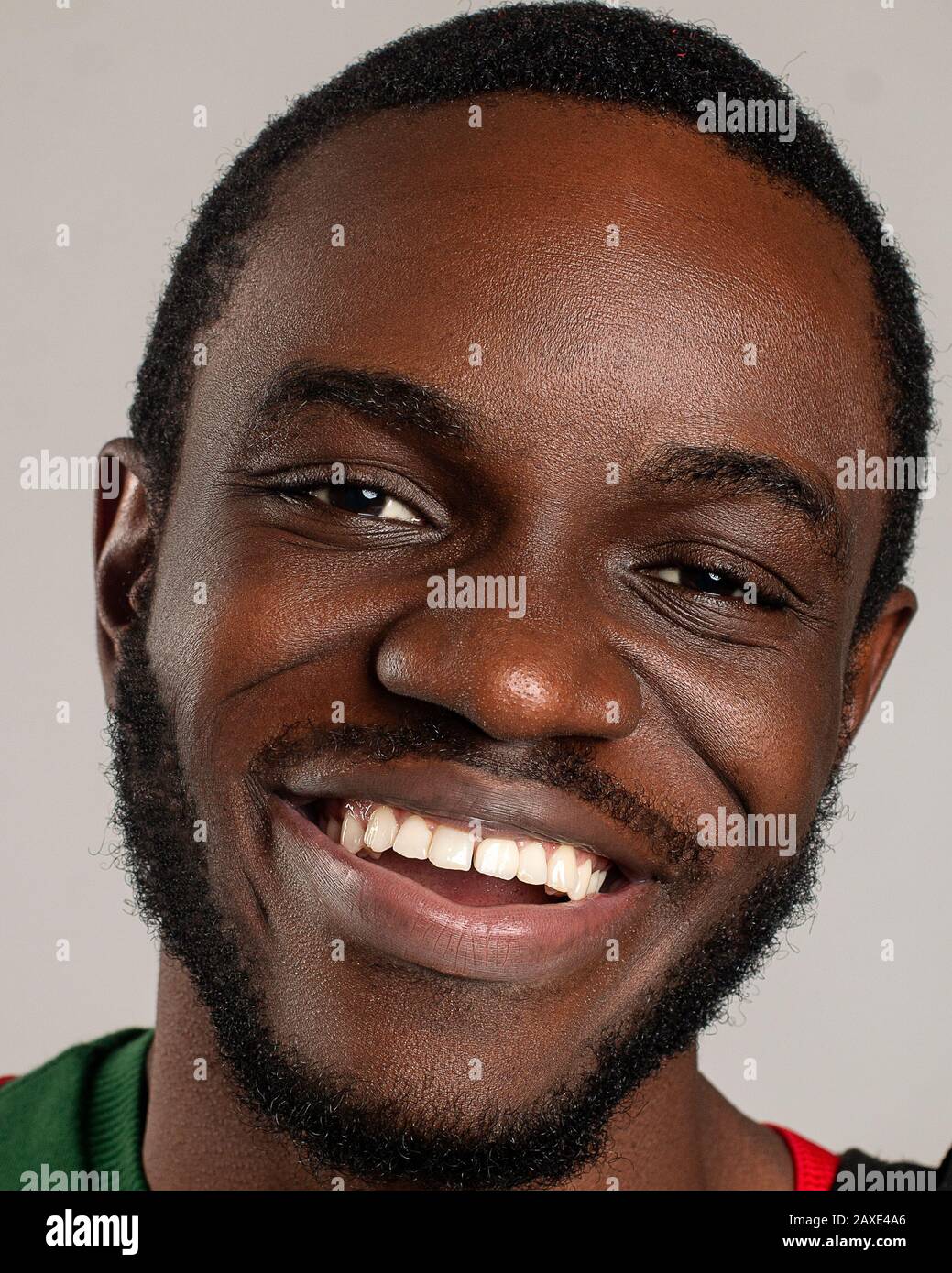 Gros plan portrait d'un jeune afro-américain souriant positivement avec de belles dents et regardant directement sur un fond gris Banque D'Images