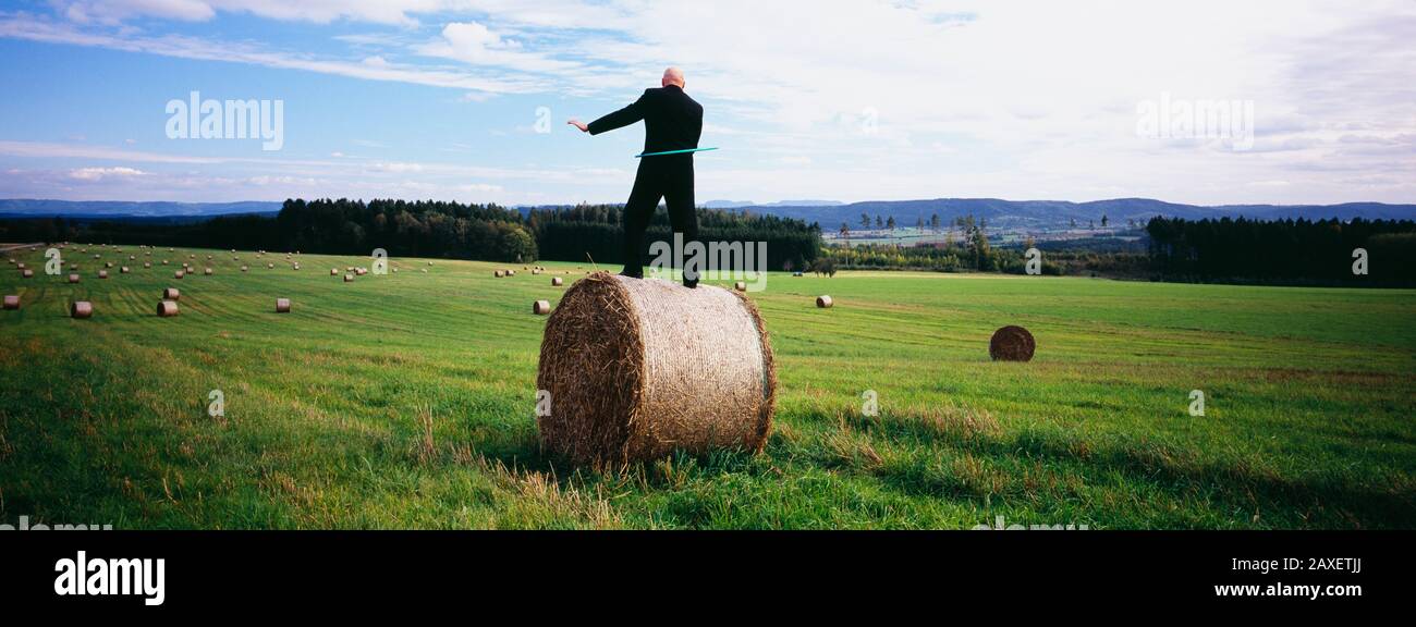 Homme debout sur une balle de foin et jouant avec une hula hoop, Allemagne Banque D'Images