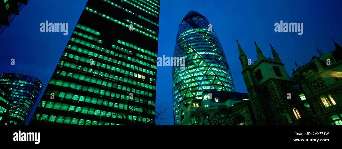 Vue à faible angle des bâtiments éclairés la nuit, édifice Sir Norman Foster, Swiss Re Tower, Londres, Angleterre Banque D'Images