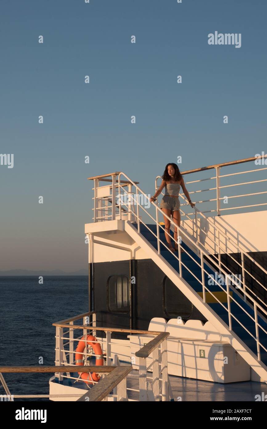 Une jeune fille en short debout sur l'escalier bleu sur le ferry à bord d'un ferry à destination de Lesvos en Grèce Banque D'Images