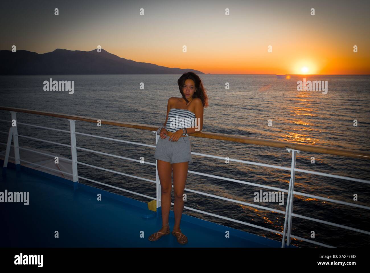 L'adolescent asiatique en métro se tenant sur la terrasse du ferry en regardant loin du coucher du soleil sur le ferry à destination de la Grèce Banque D'Images