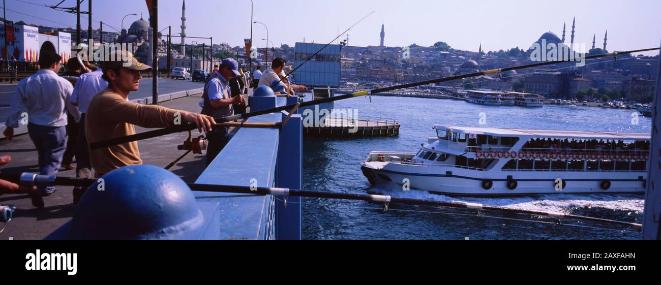 Profil latéral des pêcheurs pêchant dans une rivière, pont de Galata, Istanbul, Turquie Banque D'Images