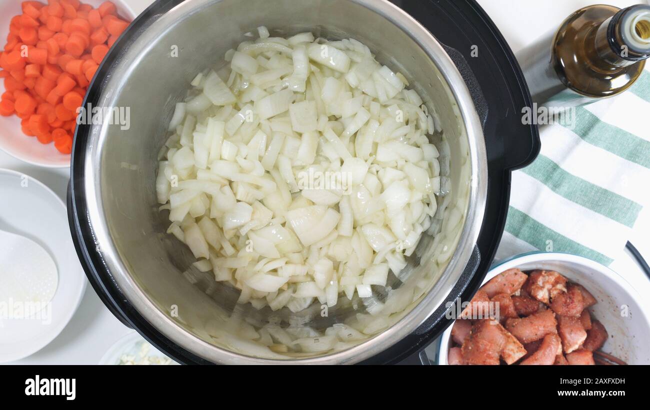 Faire sauter l'oignon haché dans un multicuiseur. Cuisson du riz avec de la viande et des légumes dans un cuiseur multi-pression étape par étape, vue de dessus. Banque D'Images