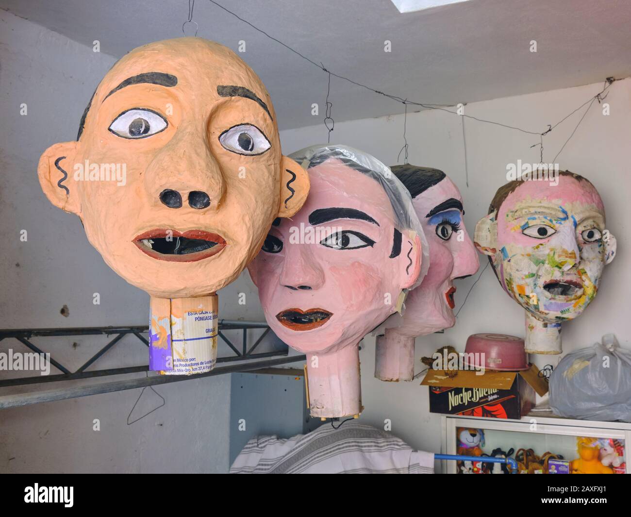 Têtes géantes en papier mâché accrochées dans un atelier mexicain, avec des visages peints et décorés Banque D'Images