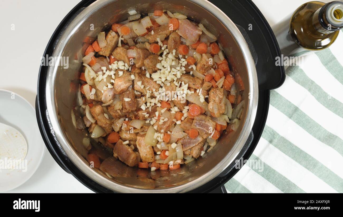 Cuisson du riz avec de la viande et des légumes dans un cuiseur multi-pression étape par étape. Ajouter de l'ail haché. Banque D'Images