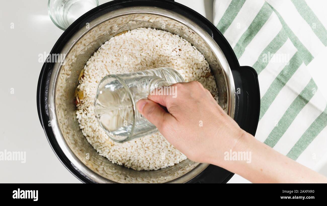 Cuisson du riz avec de la viande et des légumes dans un cuiseur multi-pression étape par étape, vue de dessus. Verser de l'eau dans un pot. Banque D'Images
